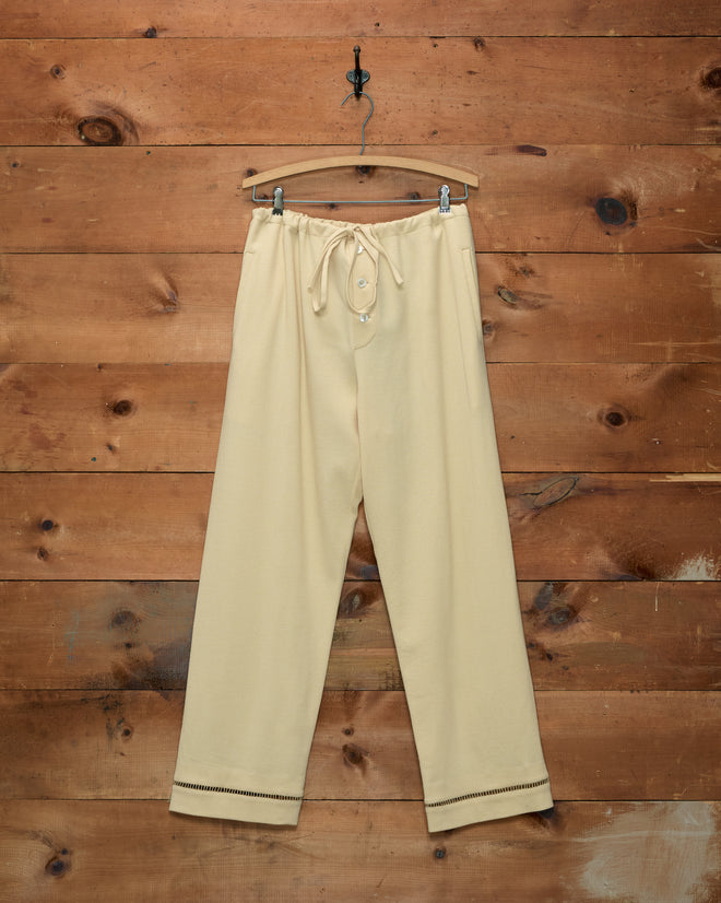 Ladder Crêpe Pajama Pants in pale yellow with ladderwork embroidery and a drawstring waist, on a wooden hanger.