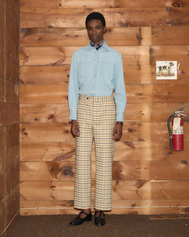 A person wearing a light blue button-down shirt and Sandhill Plaid Trousers in a classic checked silhouette.