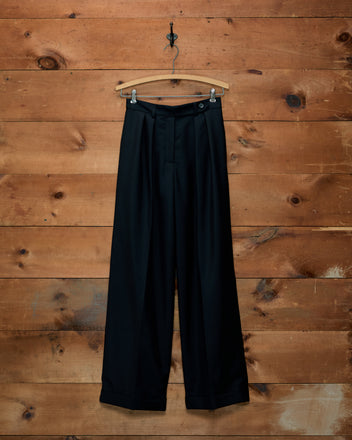 Sonora Mohair Trousers in black, featuring wide legs, front pleats, and cuffs, hanging on a wooden hanger.