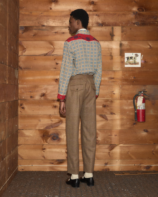 Person from behind wearing brown Fremont Herringbone Trousers and a plaid shirt with red accents.