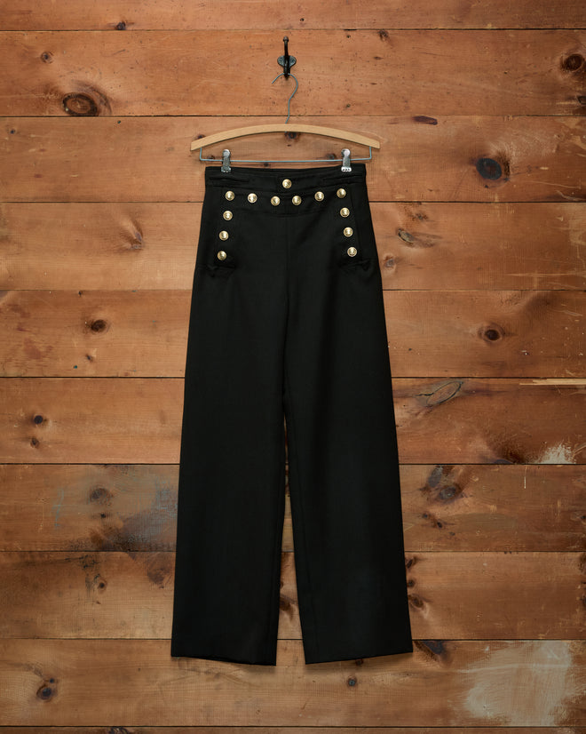 Cavalry Sailor Trousers in navy, high-waisted with double rows of gold horsehead buttons, hanging on a hanger.