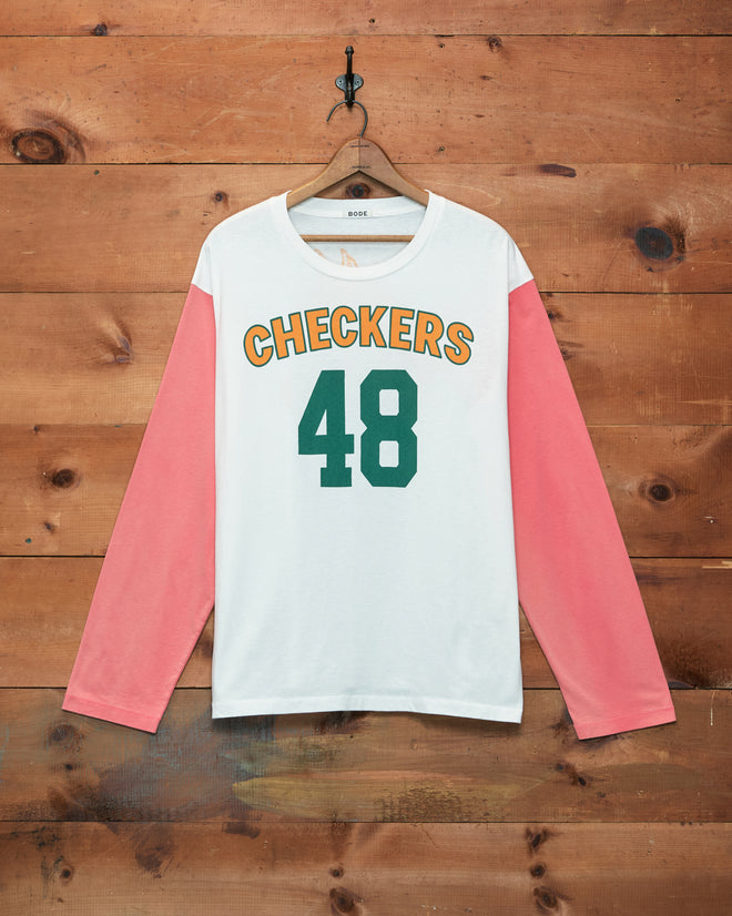 Checkers Baseball Tee with “CHECKERS 48” on the front—yellow text, green number, pink long sleeves, and made from 100% cotton; presented against a wooden background.