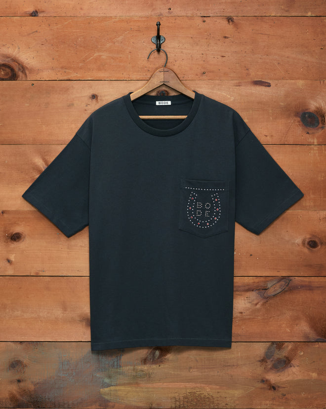 A black Horseshoe Stud Pocket Tee with a stitched pocket on a wooden wall; “BOY” is outlined in silver studs on the pocket.