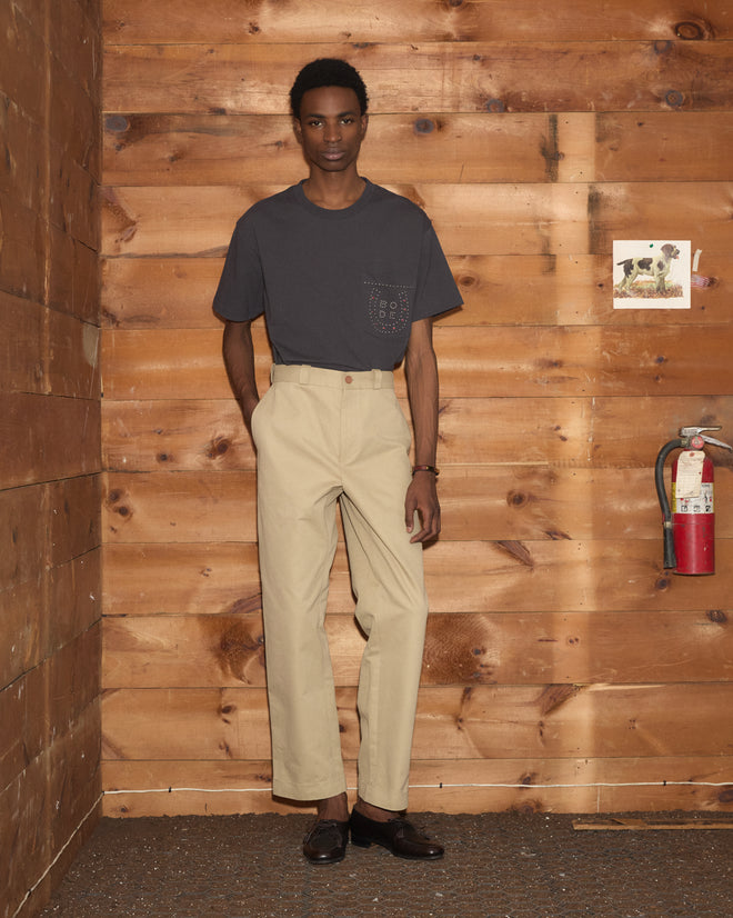 A person wearing Campus Trousers - Khaki and a dark gray T-shirt with a pocket.