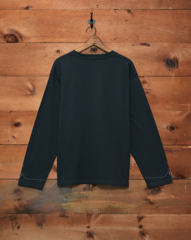 Silver Stud Long Sleeve Tee in black, heavyweight and long-sleeved, displayed on a hanger against a wooden wall with the back facing forward.