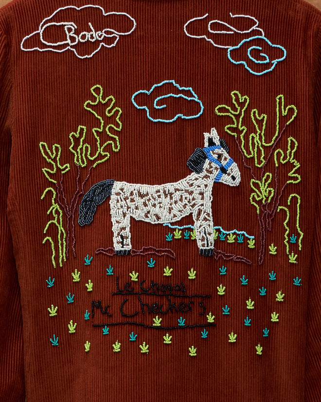 Brown Cheval Corduroy Jacket with hand-beaded embroidery of a horse, trees, clouds, and “Le Cheval Mc Chackers” text.