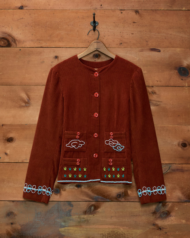 Cheval Corduroy Jacket in rust-colored cotton with embroidered cloud and plant motifs, button front, and two pockets.