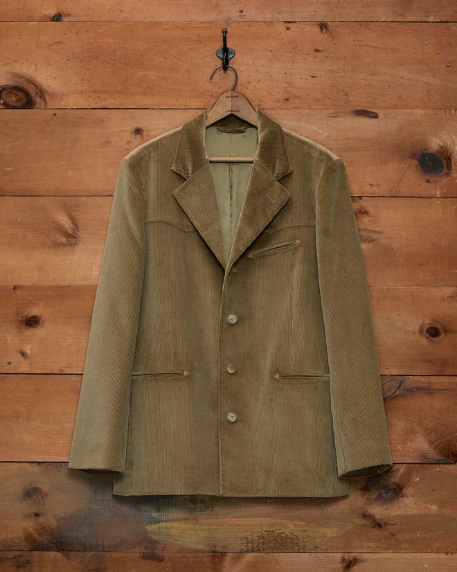 Western Corduroy Suit Jacket in olive with western-style pocket details hanging on a wooden wall.