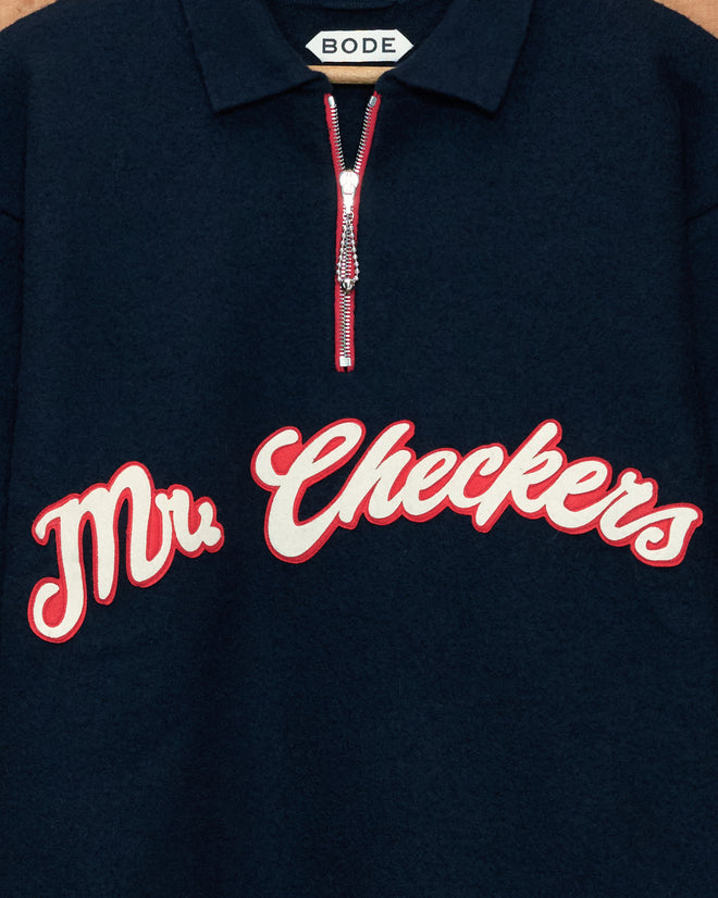 The Mr. Checkers Felted Pullover is a navy quarter-zip sweater featuring “Mr. Checkers” in red and white script and a zippered collar labeled “BODE,” crafted from 100% wool for a refined, rodeo-inspired style.