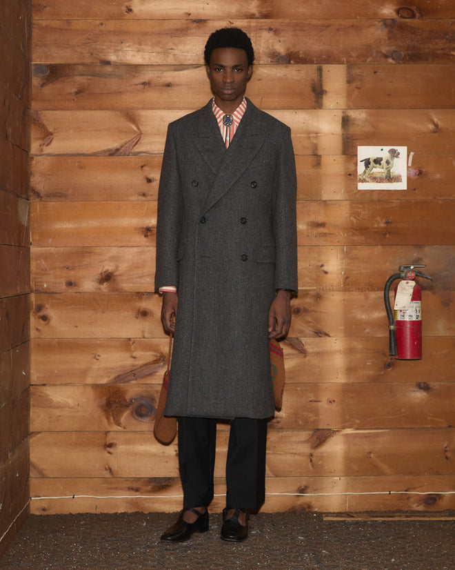 A man in a grey Buffalo Tweed Coat over a striped shirt and bolo tie.