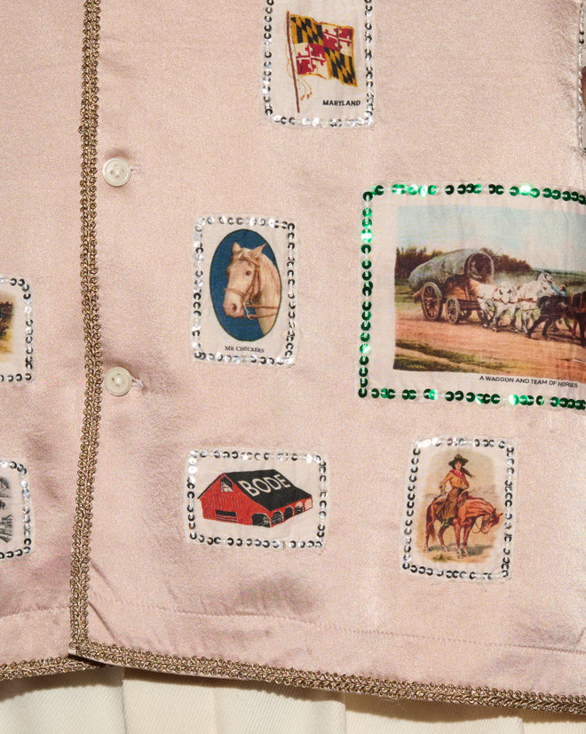 The Equestrian Patch Long Sleeve Shirt features pink fabric adorned with Maryland patches, horses, barns, cowboys, and wagon motifs, all bordered by sequins and buttons—an ideal choice for collectors of reproduction silk shirt designs or anyone seeking a distinctive garment reminiscent of vintage tobacco silks.