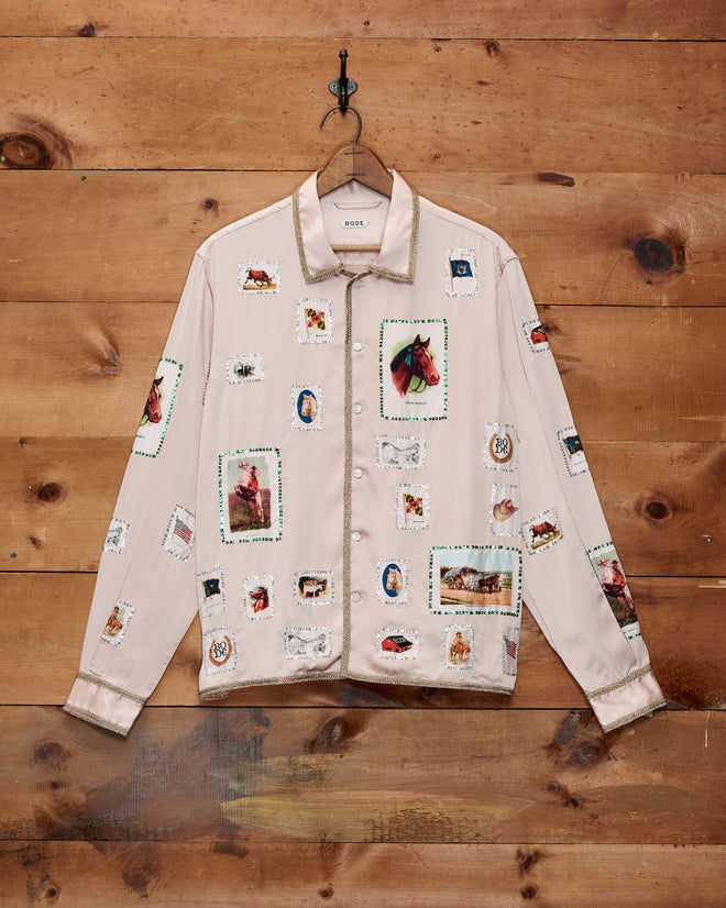 Equestrian Patch Long Sleeve Shirt in beige, featuring vibrant postage stamp-inspired prints reminiscent of vintage tobacco silks, displayed on a wooden wall.
