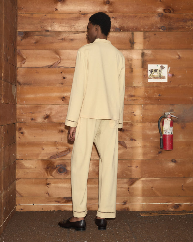 Person in a pale yellow Ladder Crêpe Shirt and matching trousers with ladder-stitch detailing on the cuffs.
