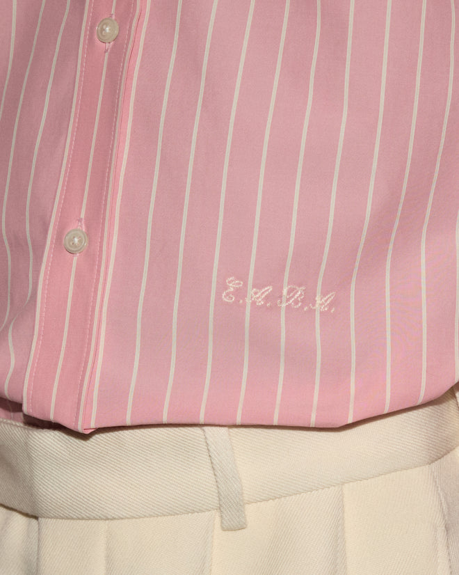 A pink and white striped Pickfair Shirt with “E.A.R.L.” embroidered, featuring a contrasting white collar and tucked into cream pants.