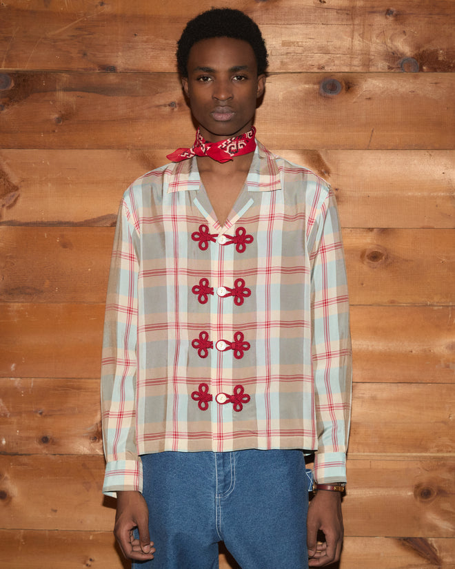 Wearing the Canyon Trillium Shirt, blue jeans, and a red bandana, a person stands against a wooden wall, facing forward.