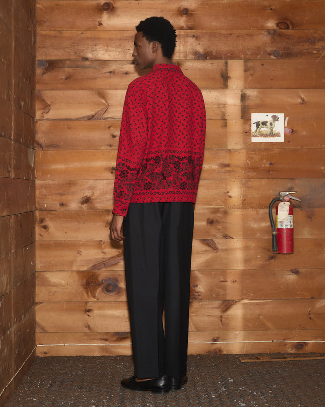 A person wearing the Beaded Kerchief Long Sleeve Shirt and black pants stands facing a wood wall with a fire extinguisher.
