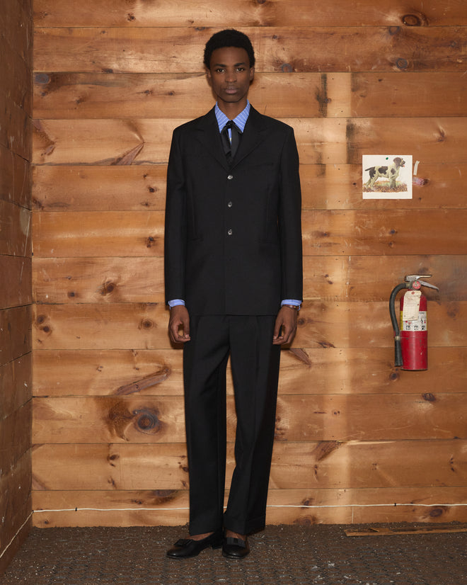 A person wearing a wool Mohair Western Suit Jacket, a light blue striped shirt, and a black tie.