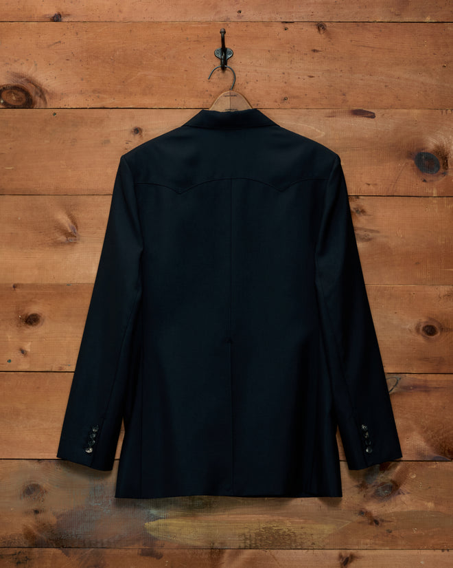 Back view of a black Mohair Western Suit Jacket with a double-pointed yoke hanging on a wall.