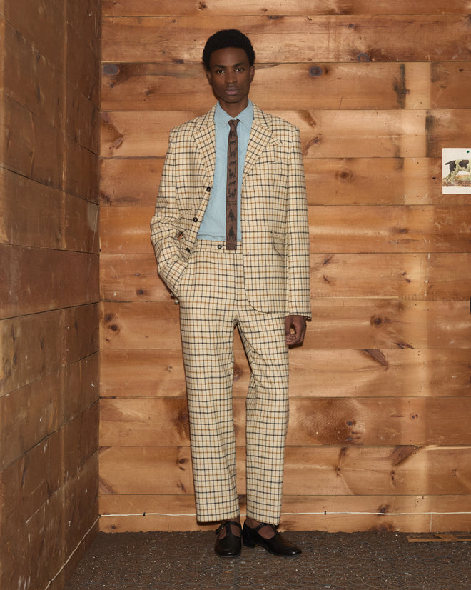 A man in a Sandhill Plaid Hacking Jacket and matching trousers, light blue button-down shirt, and a patterned tie.