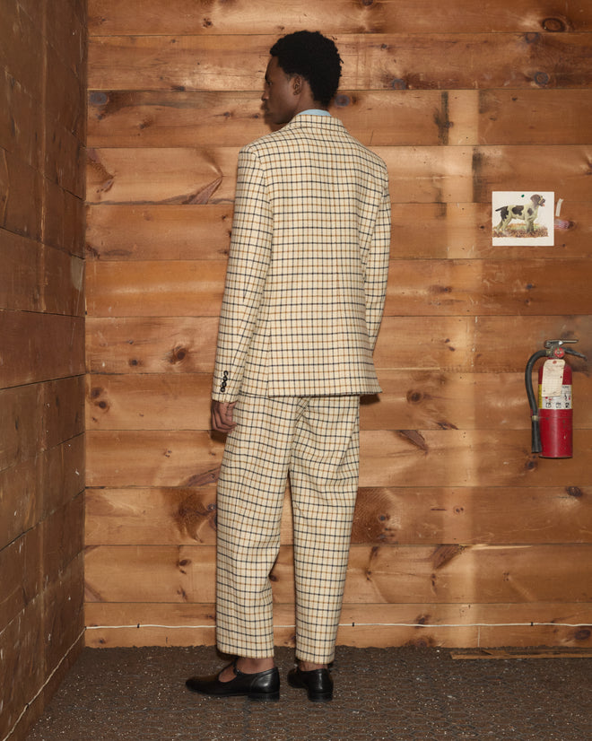A person seen from behind, wearing a light-colored Sandhill Plaid Hacking Jacket and matching trousers with shoes.