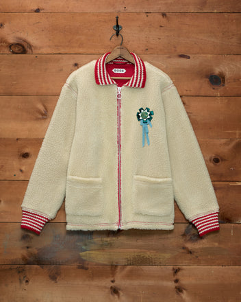 Woolly Warmup Jacket: cream-colored sherpa cardigan with a striped collar, cuffs, and a horse ribbon pin.
