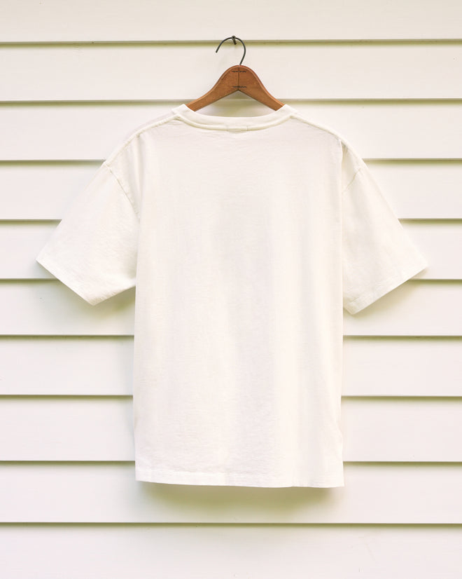 A Norfolk Stamp Tee displayed on a wooden hanger against a white paneled wall.
