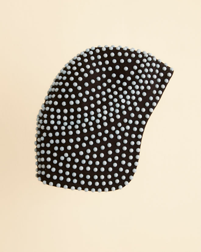 Introducing the Beaded Hat, a historical reproduction cap crafted from black fabric, adorned with a pattern of evenly spaced small white spheres against a beige background.