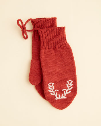 Floret Mittens - Red, handmade with a white embroidered floral design on one mitten, placed against a plain beige background.