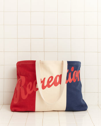 The Recreation Tote, a cotton color-blocked bag, is displayed against a tiled wall backdrop.