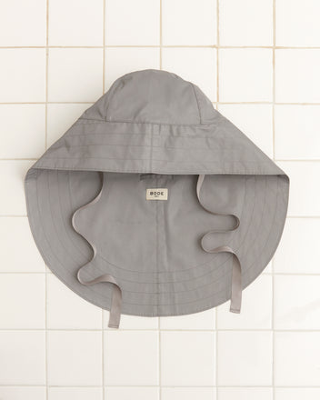 Reflective Rain Hat in gray with a wide brim and attached neck cover, displayed on a white tiled background.