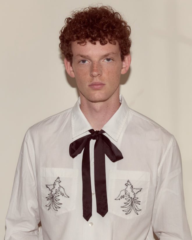 Young man with curly red hair in a white shirt with an embroidered wheat motif, styled with the Meadow Soft Tie - Black.