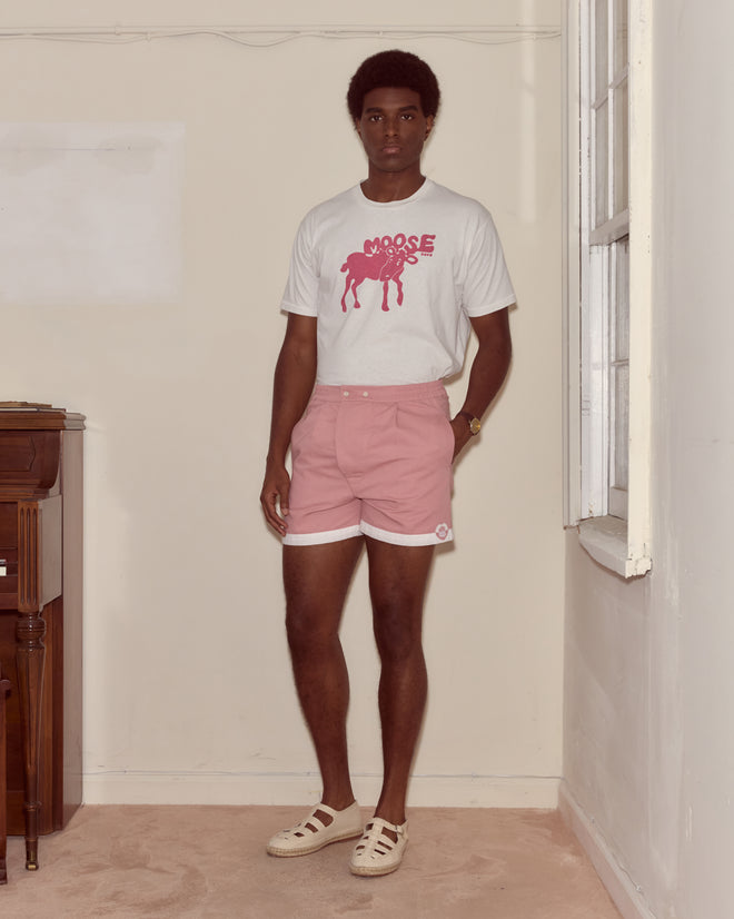 A man stands indoors by a window, wearing a white 100% cotton t-shirt with a pink graphic and Heart Deco Boxers.