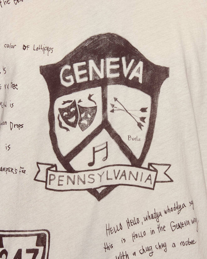 The Camp Crest Tee features a hand-drawn Geneva Pennsylvania crest with masks, arrows, and a musical note on white, plus text. Made in Portugal from 100% cotton.