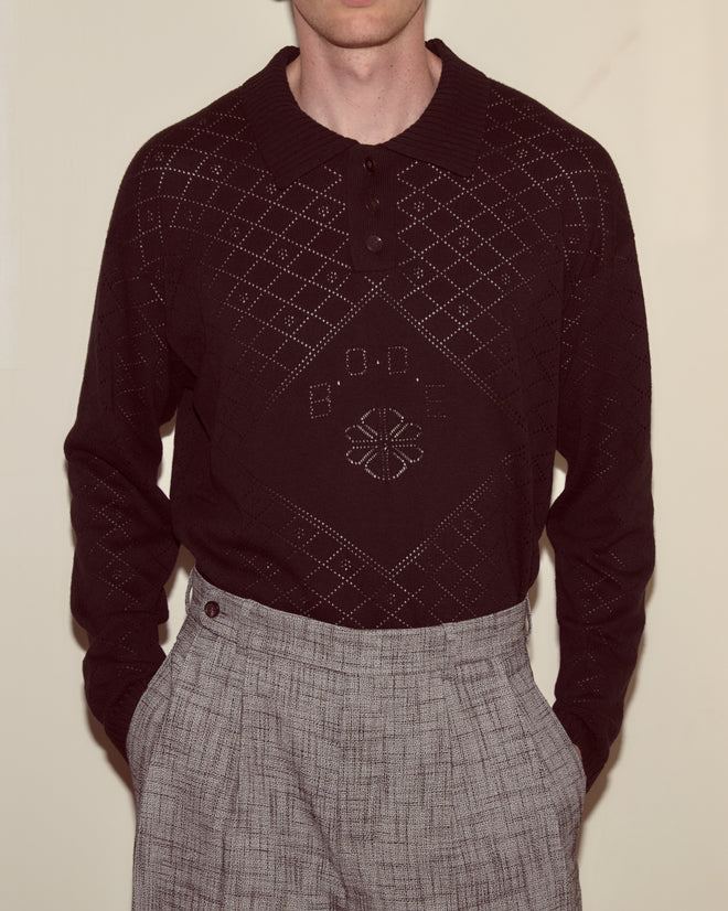 A person wearing the Anisette Polo and light gray plaid trousers, hands in pockets.