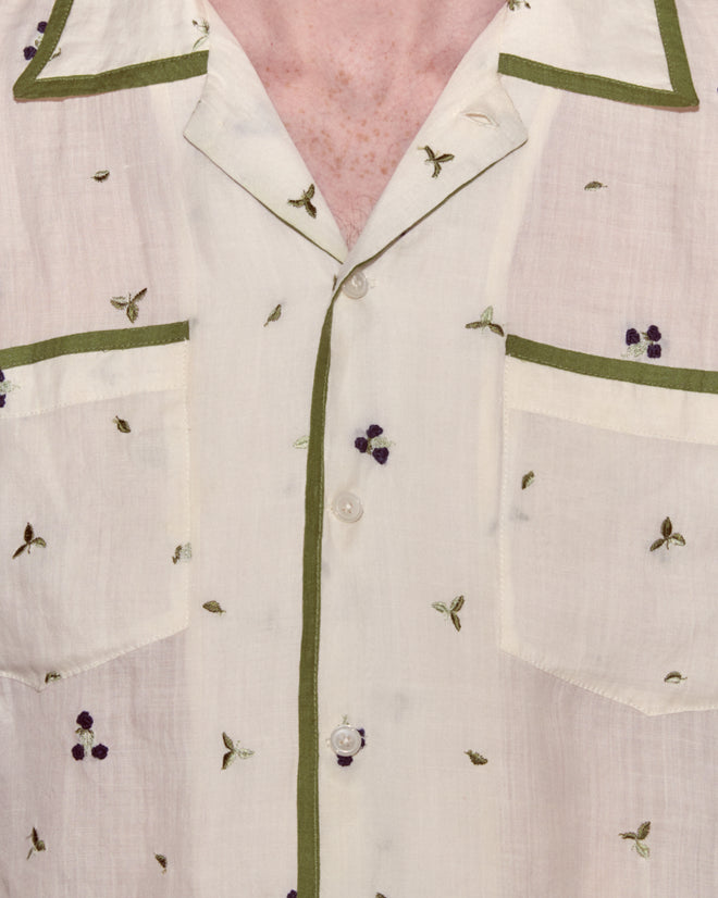 Close-up of the Blackberry Patch Long Sleeve Shirt, a linen top featuring green trim and small hand-embroidered blackberry floral designs in purple and green, made in India.