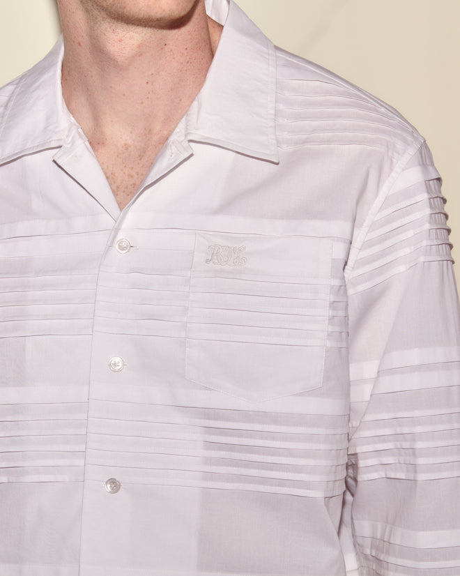 Man in the Chamomile Long Sleeve Shirt—white, striped cotton with pintuck detailing, a chest pocket, and subtle embroidered initials.
