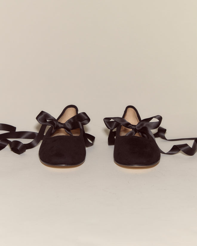 A pair of Musette Flats - Black, featuring satin ribbon ties, displayed on a light background.