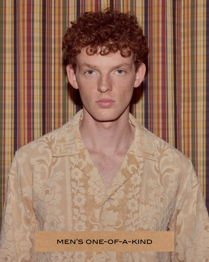A male model wearing a cream colored shirt made of an antique floral textile.