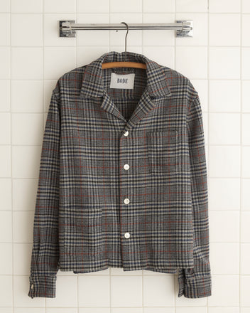 The unique Naval Glen Plaid Long Sleeve Shirt, crafted from 1960s suiting fabric, hangs elegantly against a tiled wall.