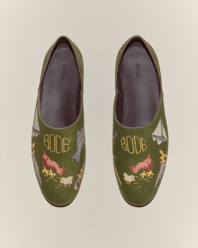 Needlepoint House Shoes: Green loafers with whimsical embroidered animals, paper planes, and "BODE," inspired by the classic Bode House Shoe and crafted in Italy for a needlepoint slipper style.