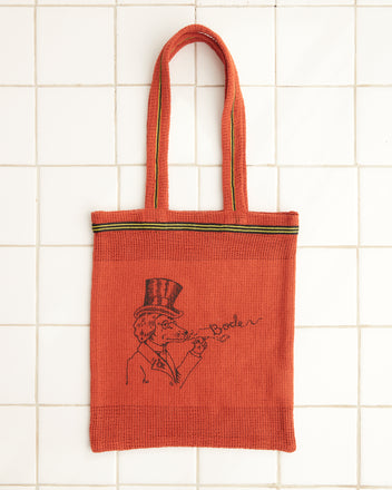 Orange Netting Tote featuring a whimsical dog illustration with a person in a top hat blowing bubbles, with 