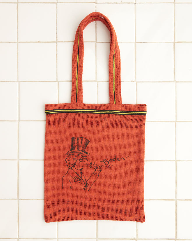 Orange Netting Tote featuring a whimsical dog illustration with a person in a top hat blowing bubbles, with 