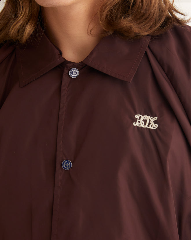 Burgandy nylon track jacket with drawstring hem and horseshoe buttons.