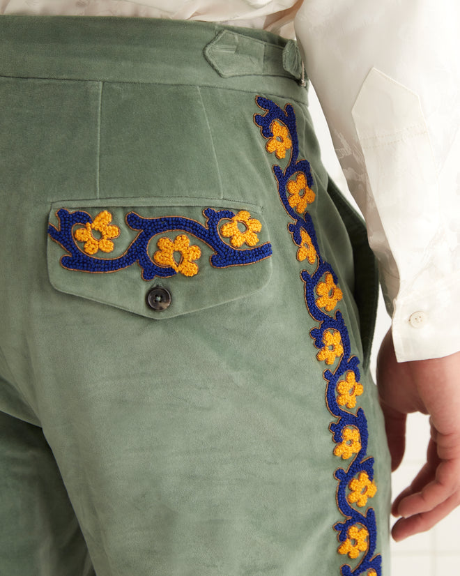 A person in a white shirt and Oberon Floral Trousers, inspired by 1930s-1940s fashion, stands against a tiled wall.