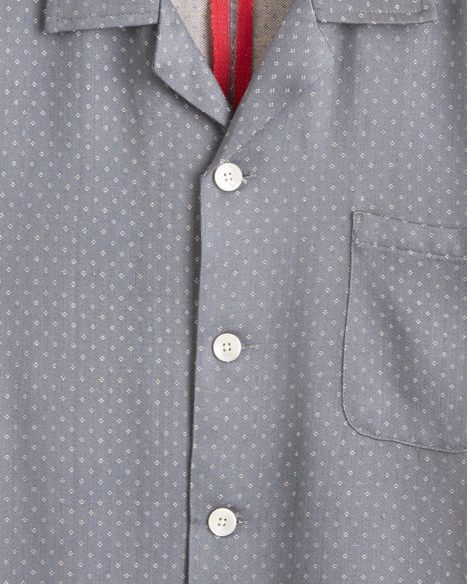 The Omura Diamond Long Sleeve Shirt - M/L, featuring a unique small dotted pattern in gray, hangs on a hook against a light-colored wall.