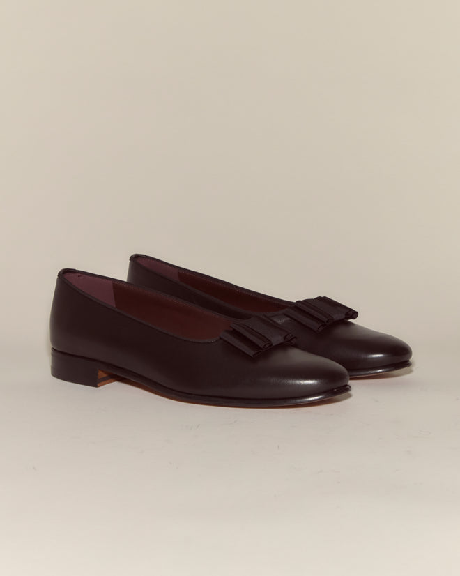 The Opera Pumps are black Napa leather shoes with bows on top, shown against a plain light background.