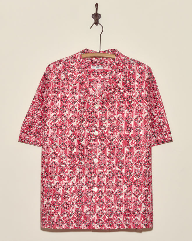 Organic Geometry Shirt (XXL): A short-sleeve, button-up deadstock shirt with a red and white geometric pattern, displayed on a hook against a beige wall.
