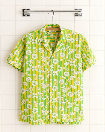 The Peaking Floral Stripe Shirt (M/L) features short sleeves, green and yellow stripes with a white floral pattern, and is crafted from deadstock fabric. Shown hanging on a metal hanger.