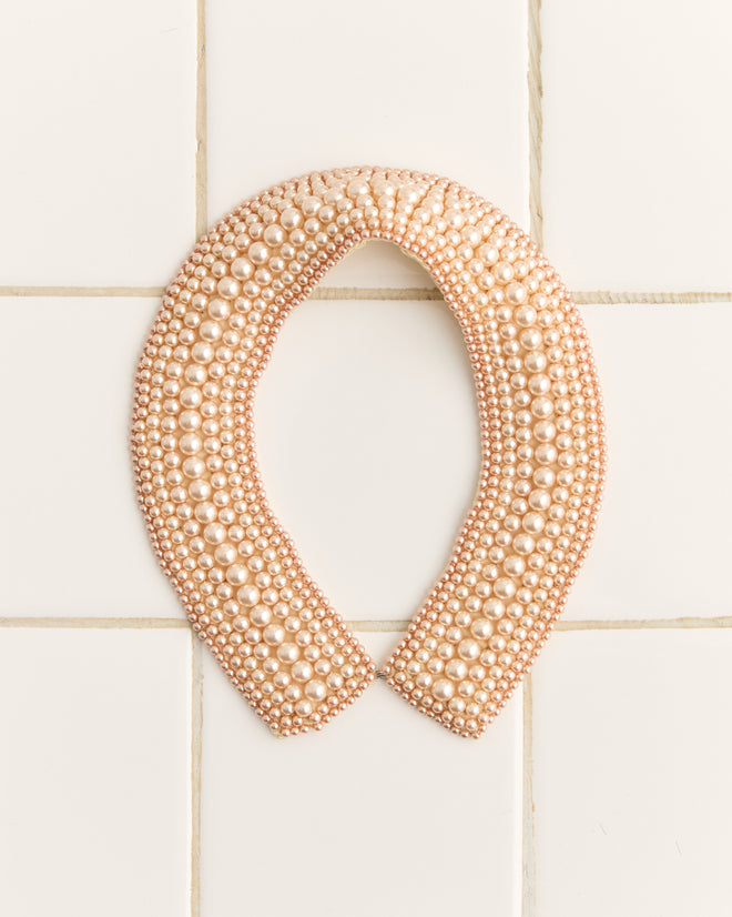 The Pearl Collar, echoing 1960s reproduction fashion, is elegantly displayed on a tiled surface.