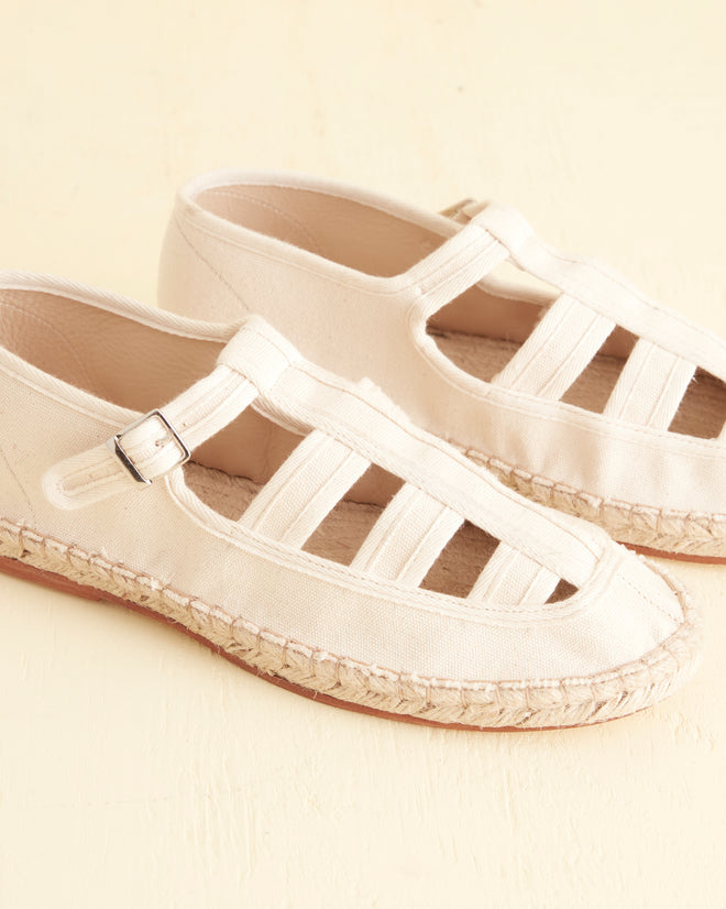 A pair of Peggy Espadrilles - Natural with woven espadrille soles and a cut-out design placed together on a light surface.